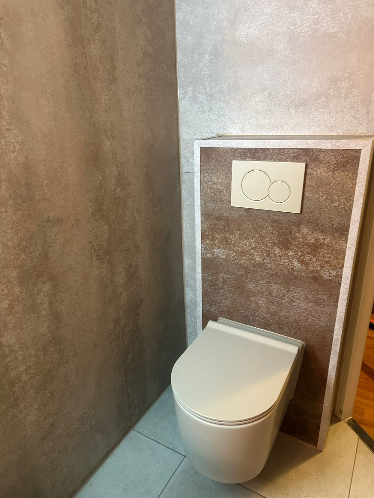 Badkamer met wandpanelen: hangend toilet en betonlook wanden